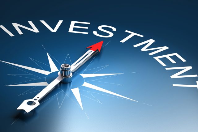 a compass pointing to the word investment on a blue background.
